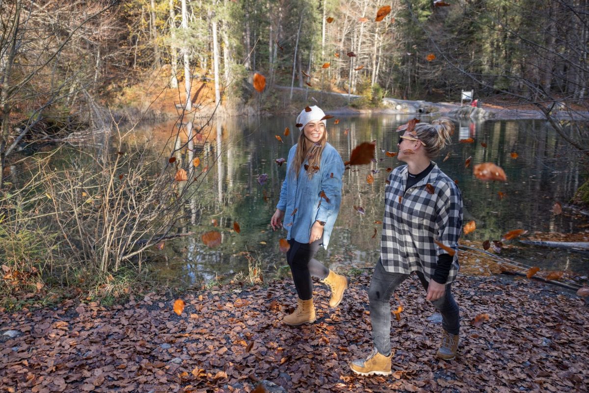Couple walking beside a forest lake surrounded by autumn colours in Haut-Giffre