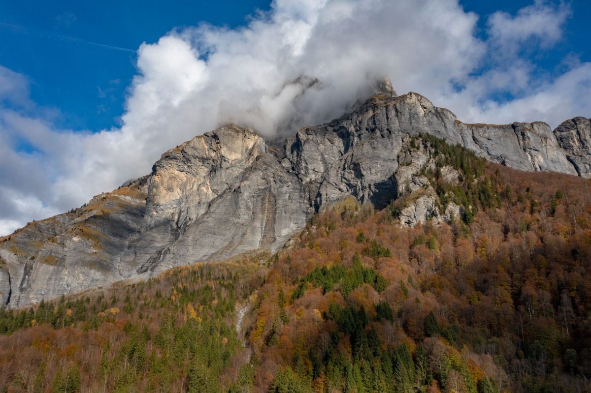 Cliffs of the Cirque du Fer-à-Cheval above autumn forests under a blue sky